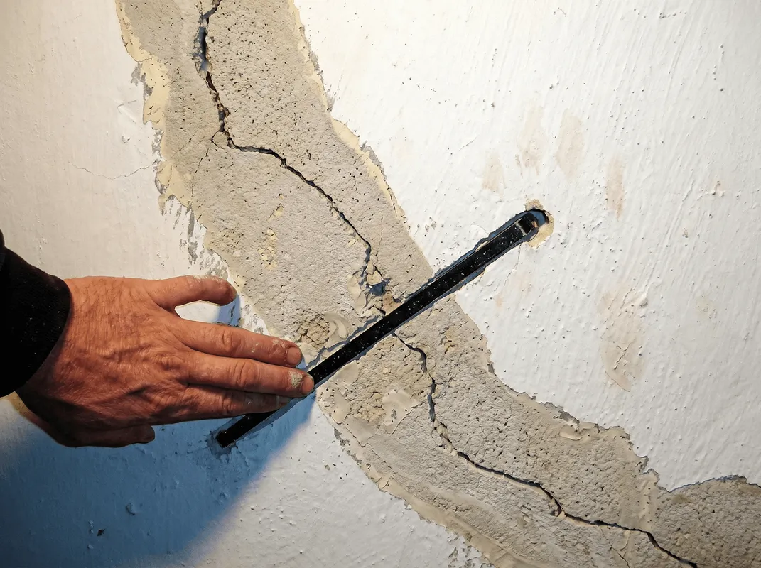 A wall with a large crack is being inspected by a professional in Seattle, WA